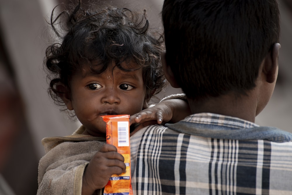 enfant en bas âge tenant un paquet orange