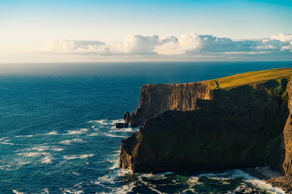 green and brown mountain beside sea under white clouds and blue sky during daytime