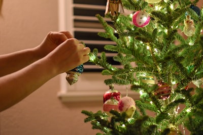 person putting baubles on christmas tree ornaments teams background