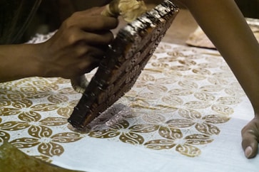 person holding brown metal manual printing stamp