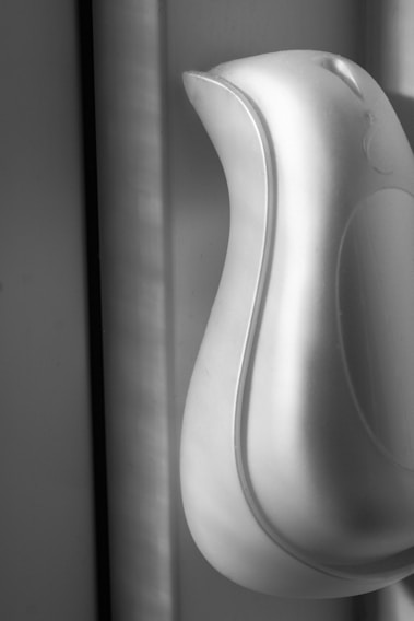 Close-up of a sleek, matte black kitchen drawer handle integrated seamlessly into a minimalist white cabinetry panel.