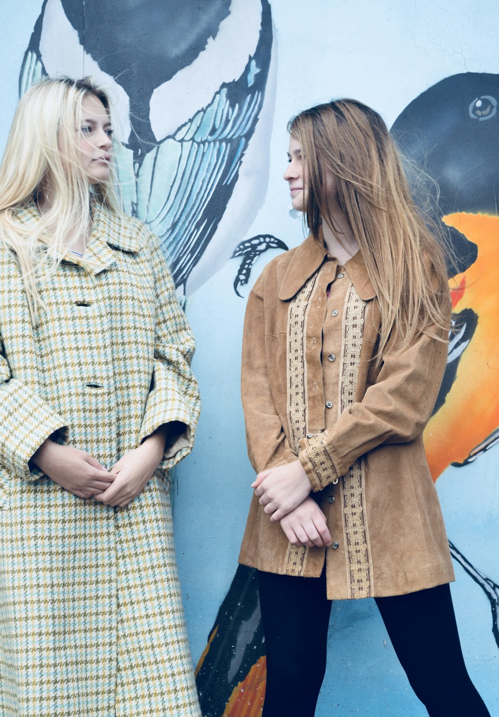 two girl's standing beside wall