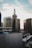 A cityscape featuring a prominent historic building with a rooftop sign that reads 'CENTER CENTER'. The scene includes modern office buildings, and the sky is partly cloudy with sunlight illuminating the urban setting.