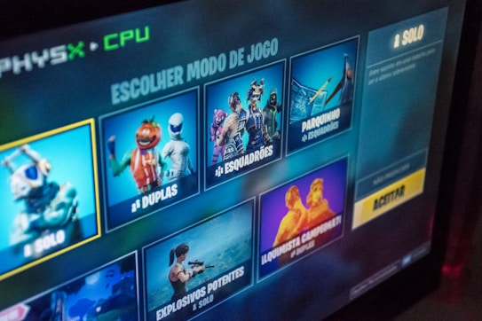 A screenshot of a video game menu showing different game modes with graphical illustrations. The menu is in Portuguese and displays options such as solo, duplas, esquadr&otilde;es, and others. Bright and colorful imagery is used for each mode, with character figures and animations.