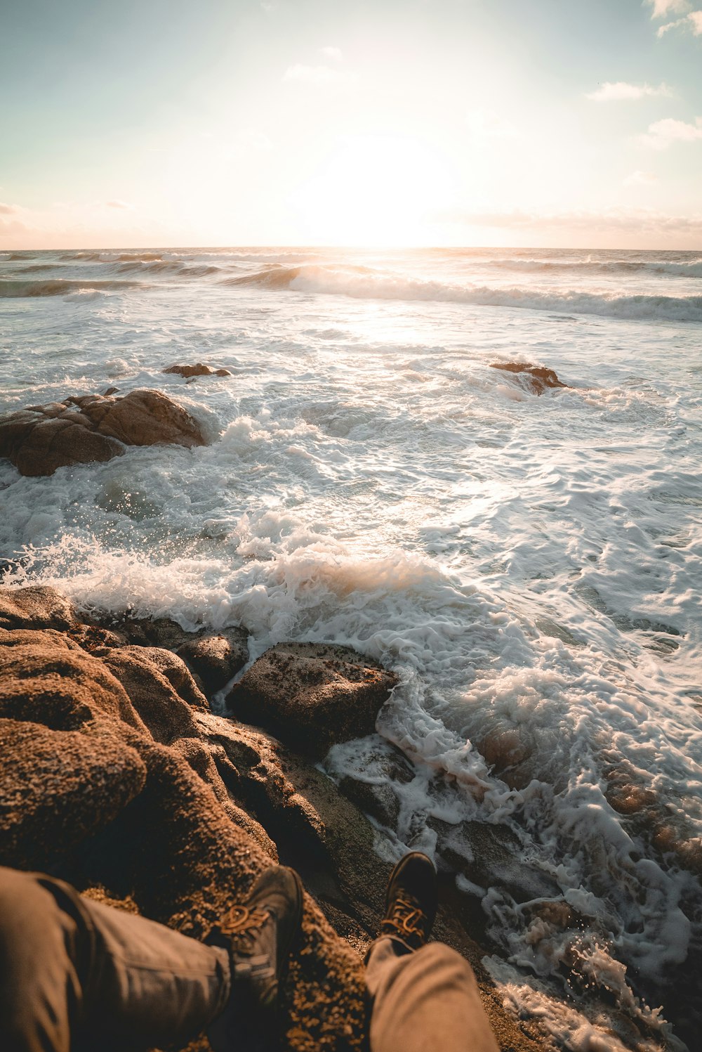 person sitting on rock beside beach