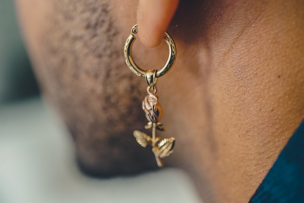 man wearing gold-colored drop earrings