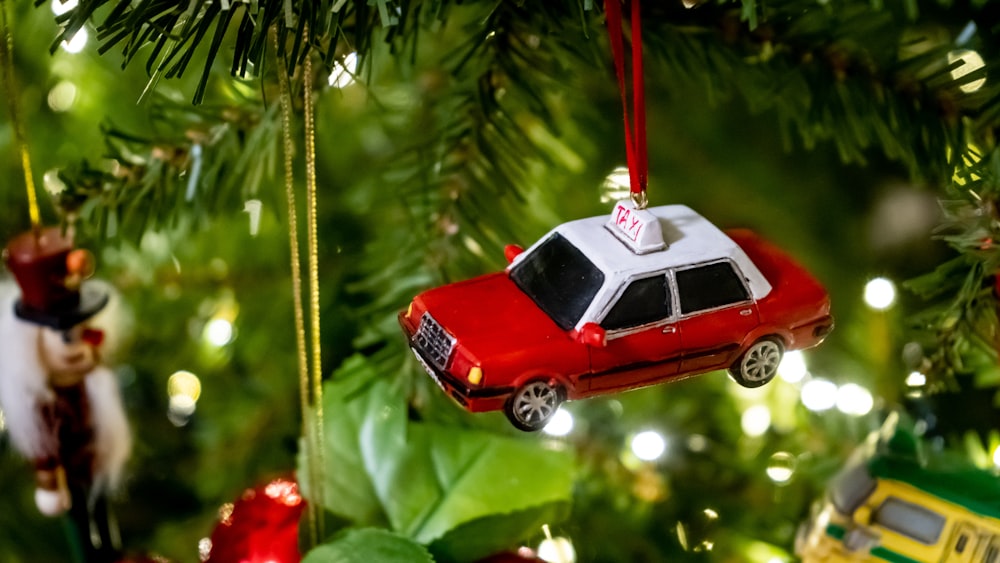 red and white car scale model hanging on green Christmas tree