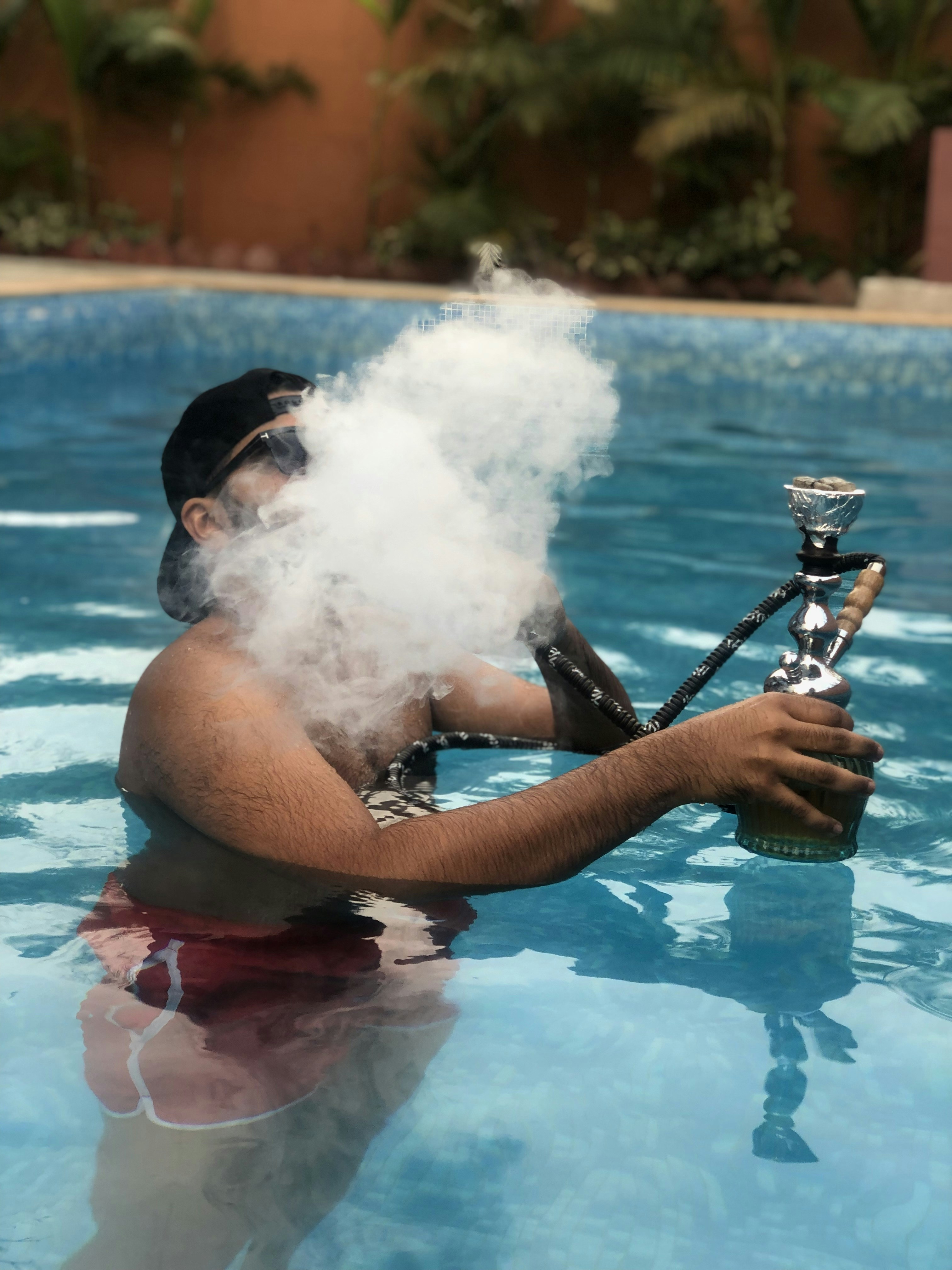 man using hookah at swimming pool \