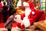 boy standing in front of man wearing Santa Claus costume