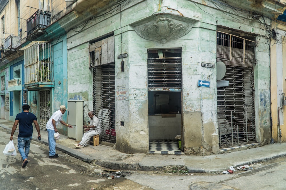 três homens ao lado de prédio de concreto cinza durante o dia