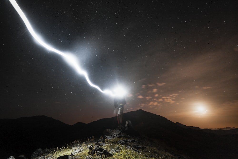 uomo in piedi sulla scogliera di notte