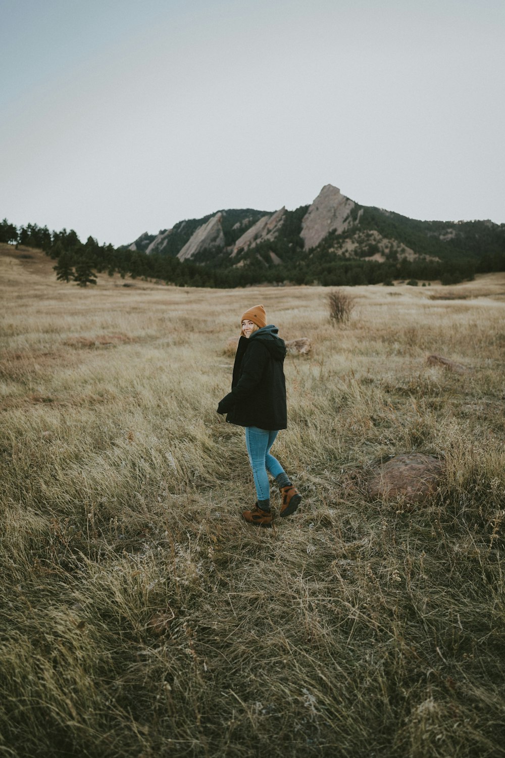 woman standing on the middle of grass field in distant of mountain