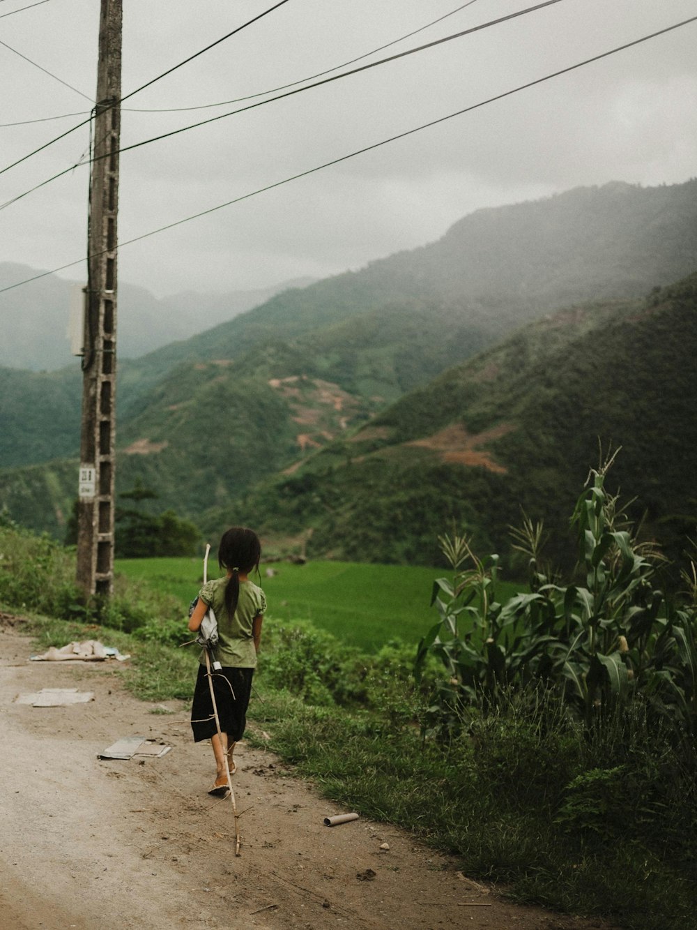 girl walking along rough road with mountain view