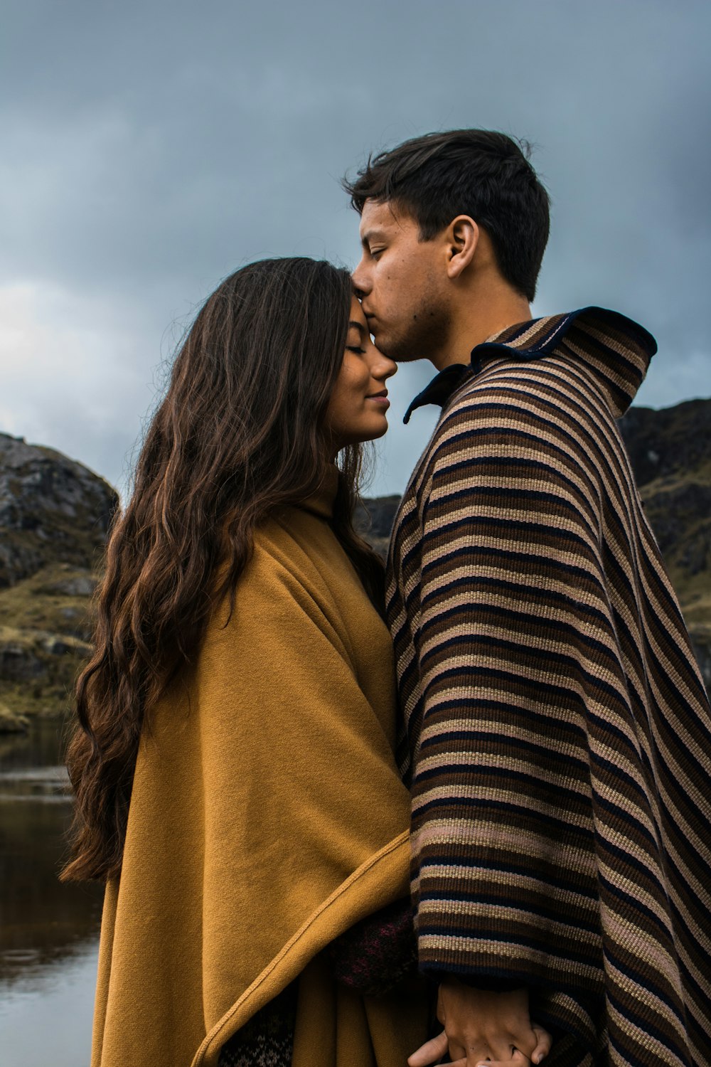 man kissing woman on forehead