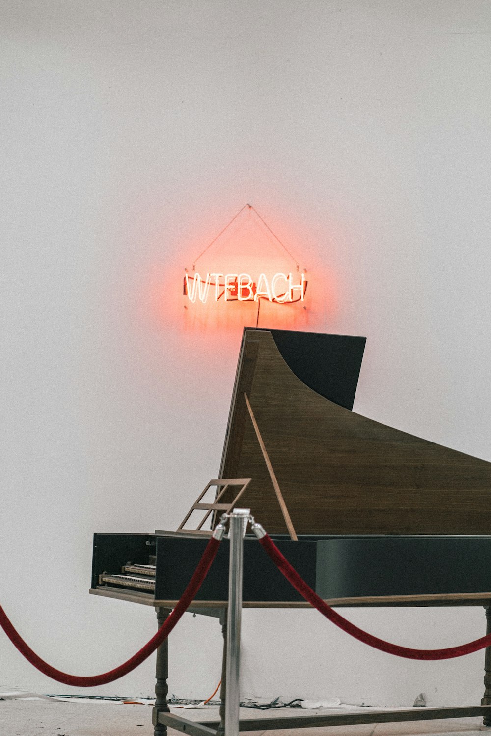 brown and black grand piano near white wall with turned-on neon signage