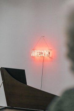Close-up of a shop sign featuring bold black and orange lettering made from vinyl letters.