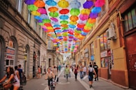 assorted-color umbrella hanged above pathway near houses
