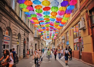 assorted-color umbrella hanged above pathway near houses