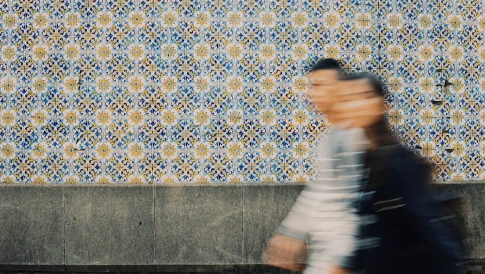 a blurry photo of a person walking by a wall
