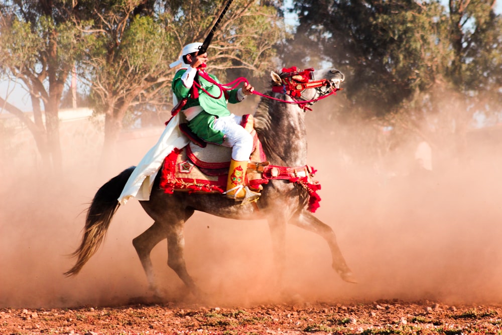 man riding horse while holding rifle