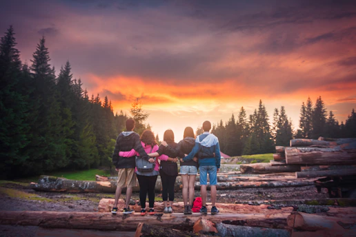 Group of joyful young people praying together outdoors at sunset.