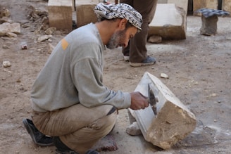 A craftsman carefully shaping a custom sidewalk with concrete and tools outdoors on a sunny day.