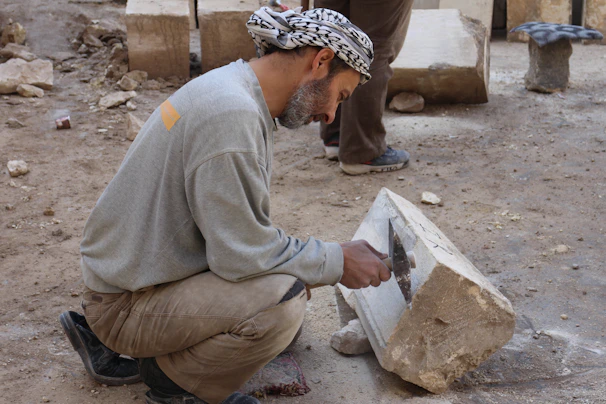 A skilled mason carefully shaping stone for a modern outdoor patio.