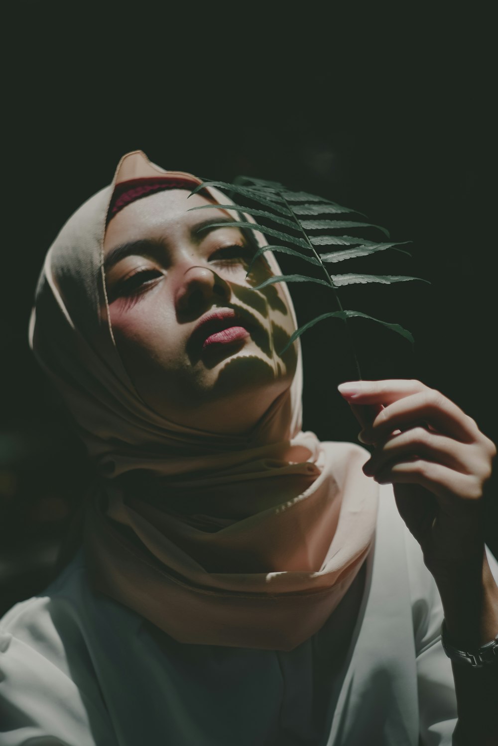 woman in hijab scarf holding leaf