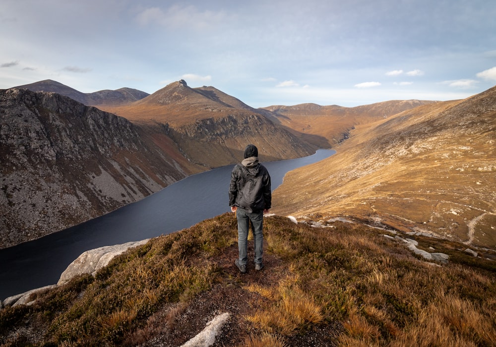 man standing on top of green grass field mountain