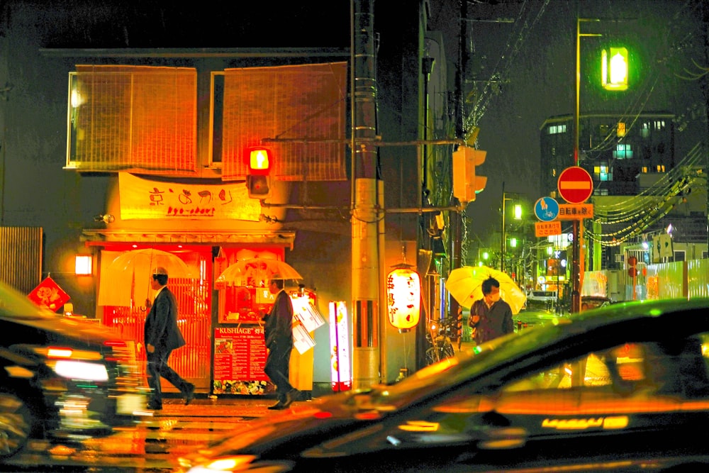 personnes marchant dans la rue tenant un parapluie sous la pluie la nuit