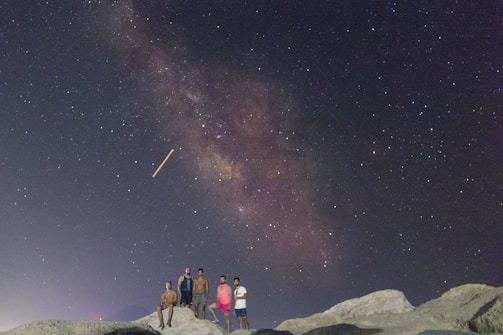 A small group of people navigating with a handmade map under starry night sky.