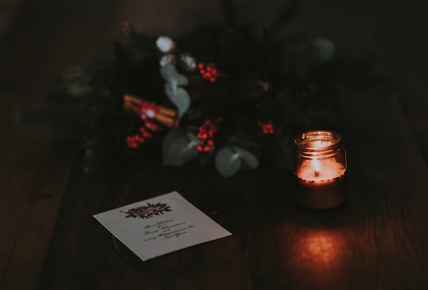 A cozy scene showing a stack of Torresea's gold-foiled Christmas cards beside a flickering candle.
