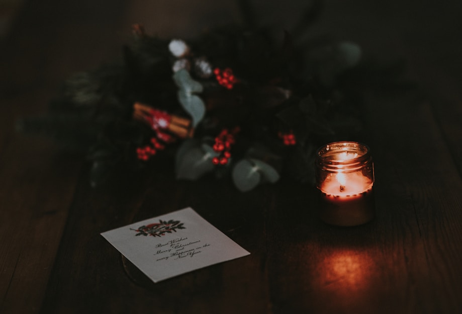 A cozy scene of a hand writing a Christmas card surrounded by festive decorations and warm lights.