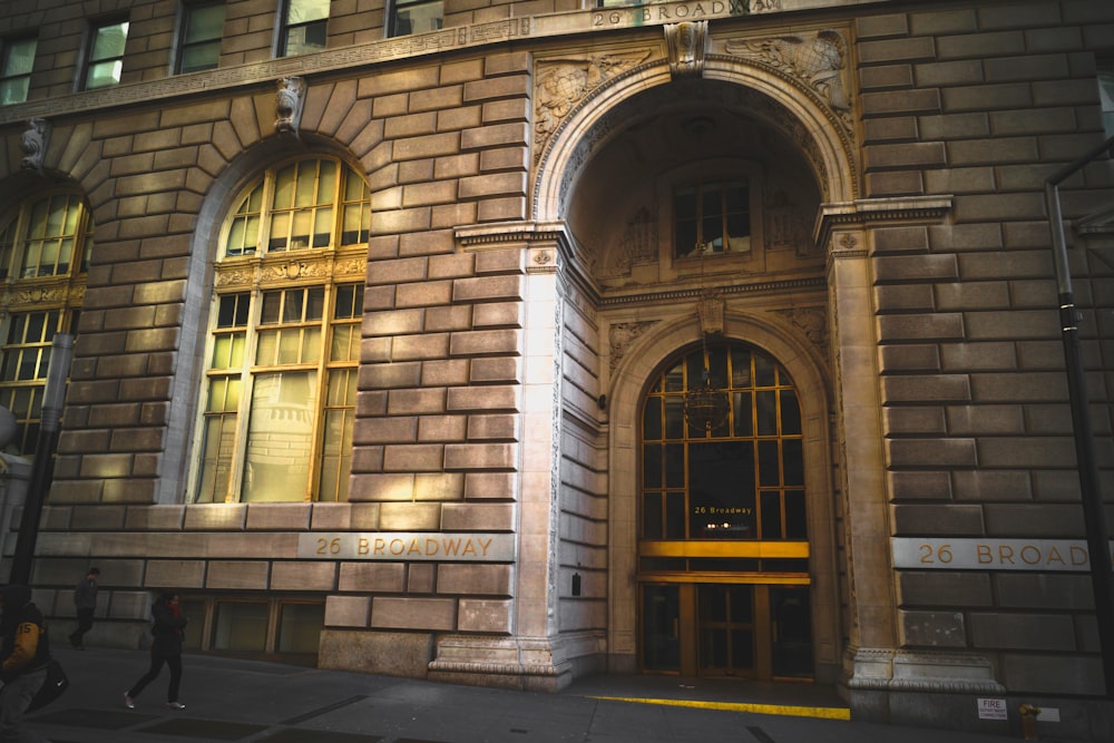 two persons walking along sidewalk of building