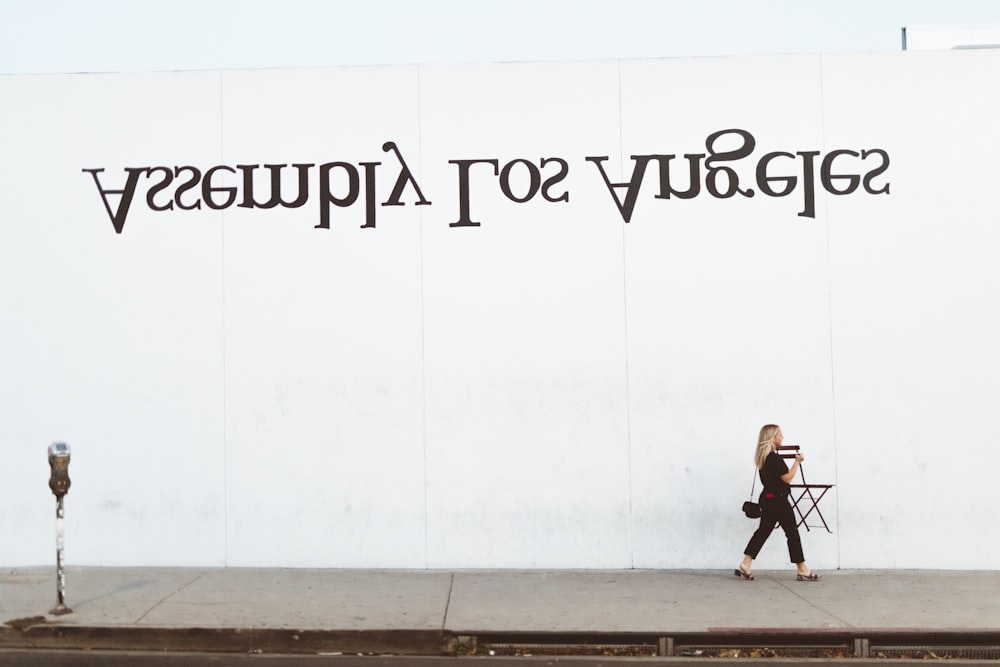 woman walking beside white painted wall