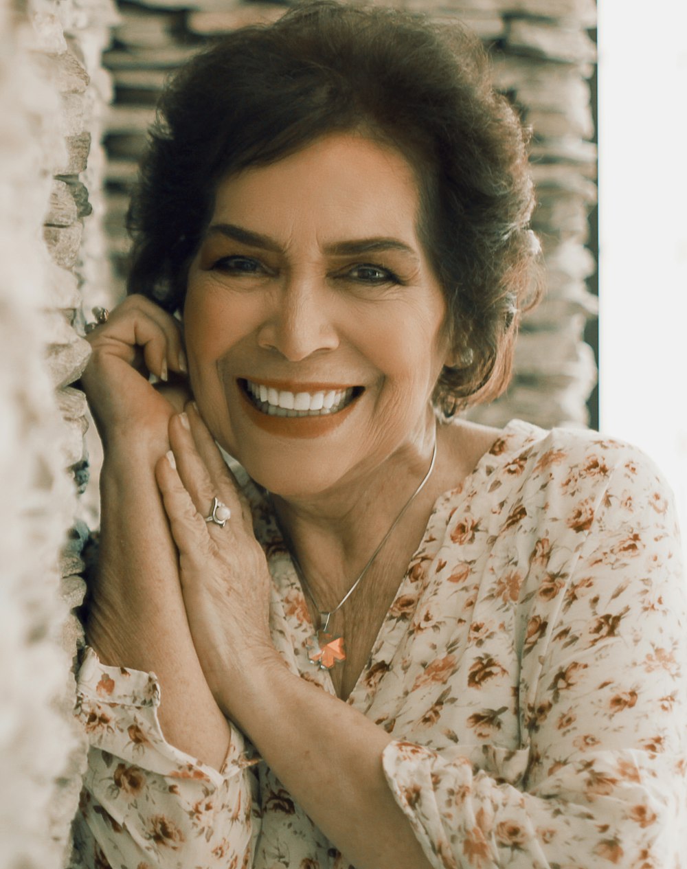 woman in white and orange floral shirt smiling