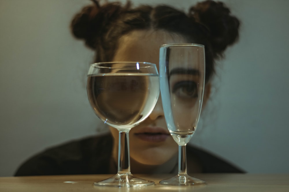 dois copos transparentes em cima da mesa perto da mulher