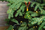 Seasonal holiday ornaments hanging from a decorated pine branch.
