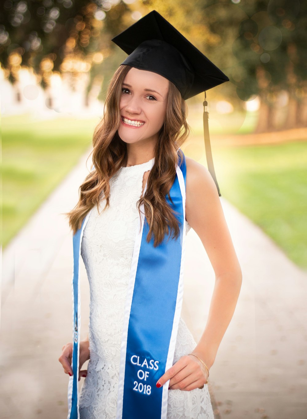 female graduate standing in middle of road