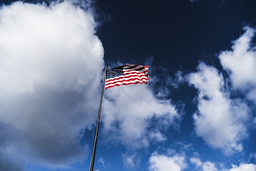 flag of America on pole under cloudy sky