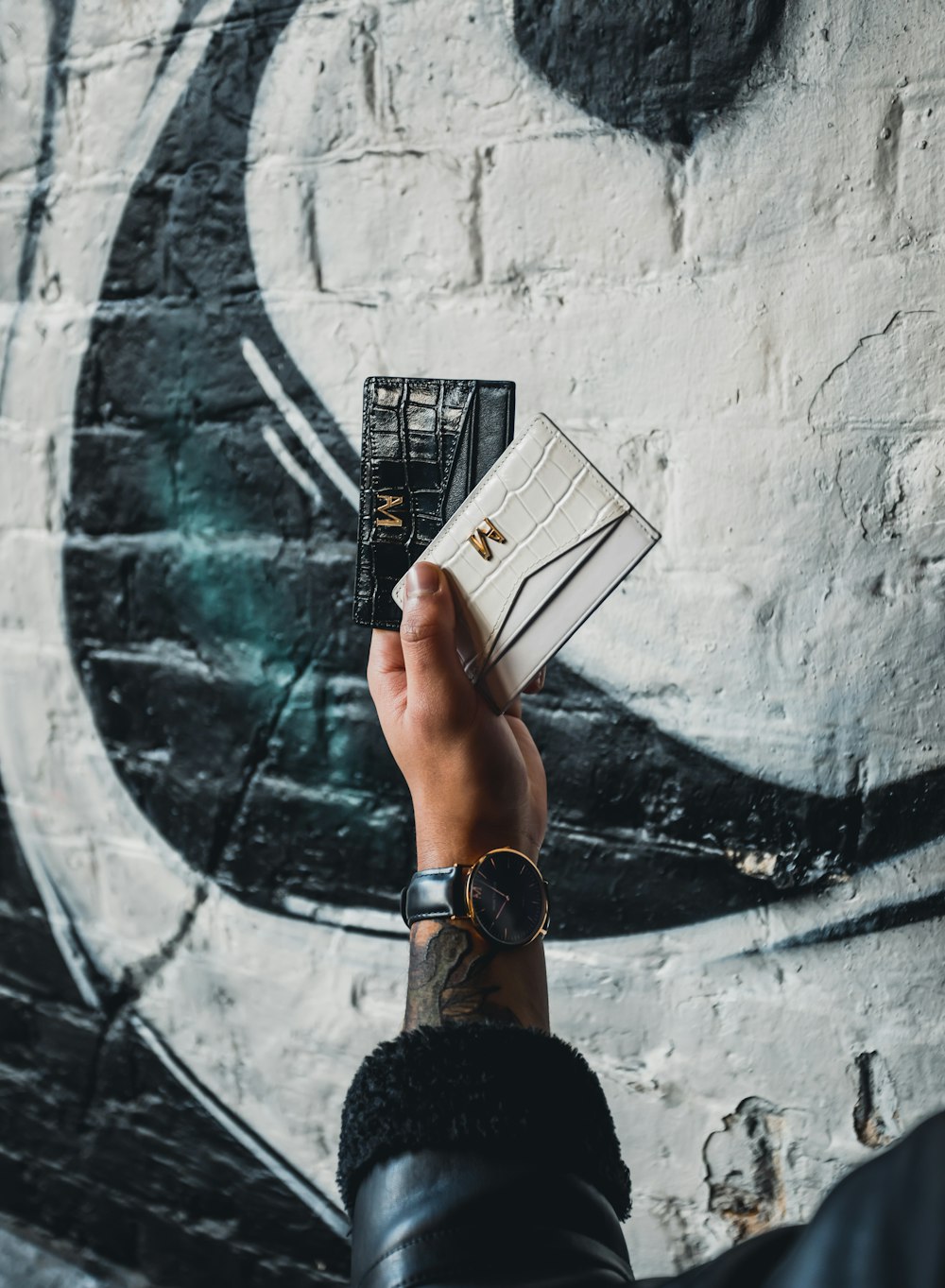 person holding black and white leather wallets