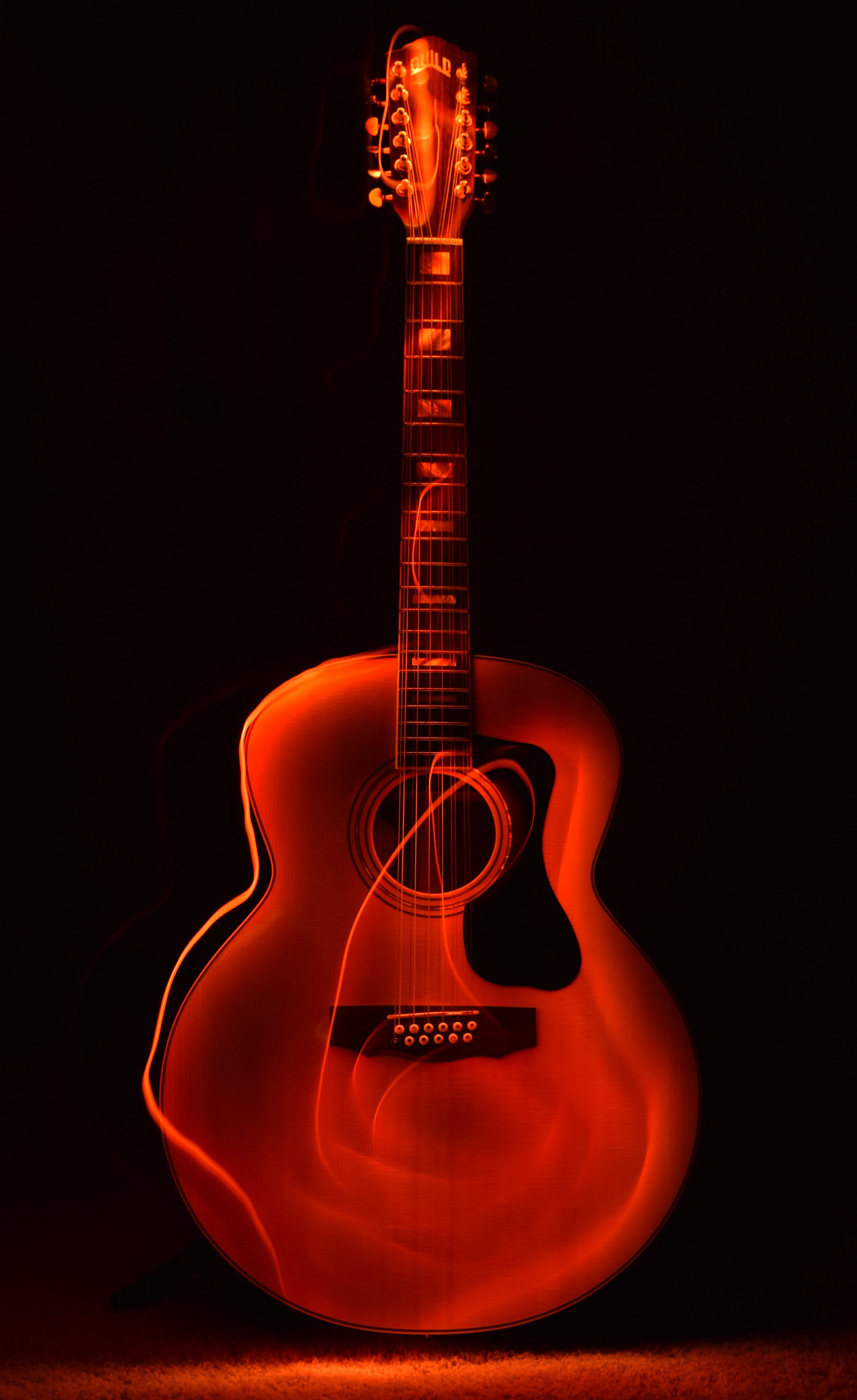 Acoustic guitar glowing under red stage light