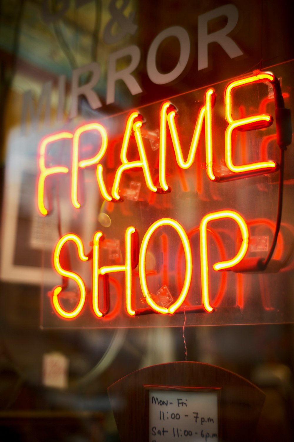 Cartelería de neón de Frame Shop encendida en la ventana