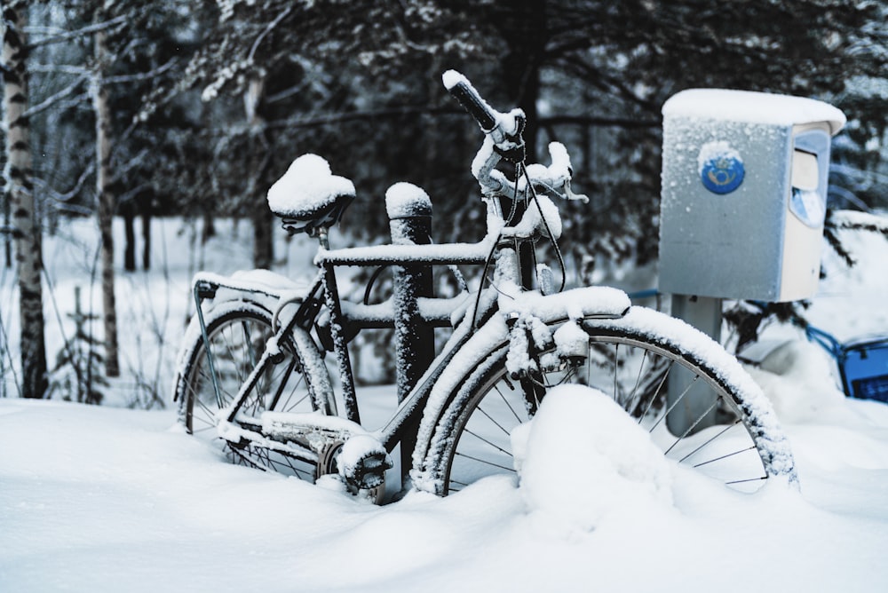 black commuter bike parked beside mail box on snow ground