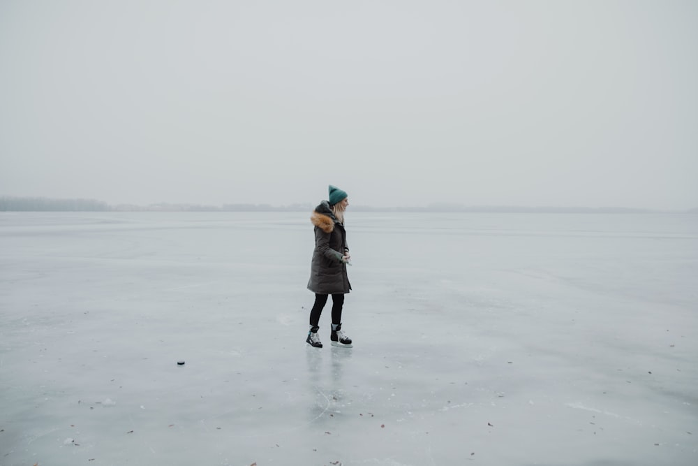 woman wearing parka coat while staining on seashore