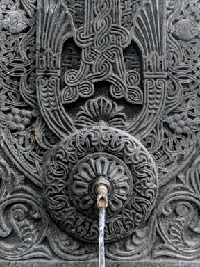 Close-up of a beautifully carved stone sink with water gently flowing.