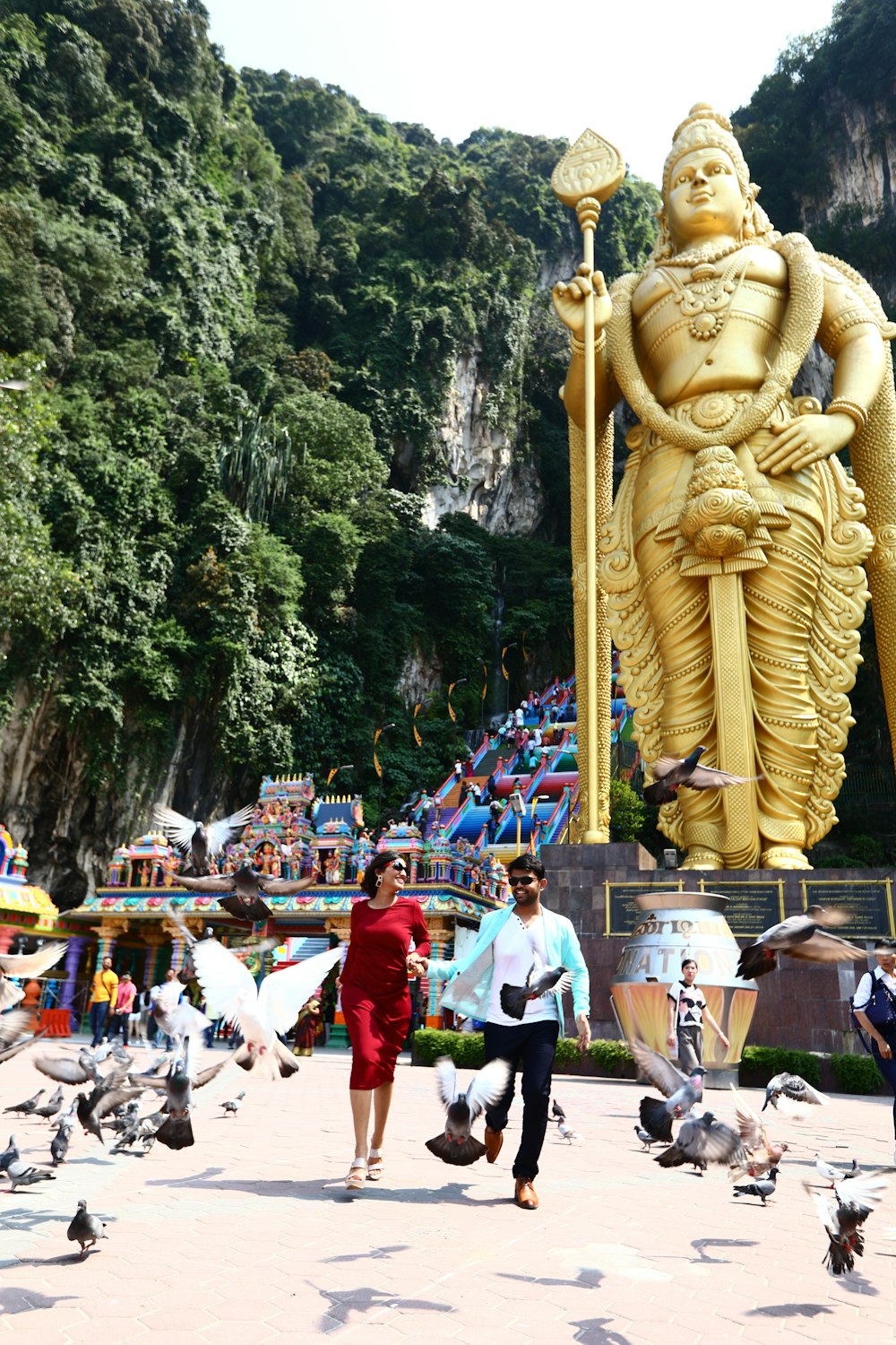 man and woman walking near buddha