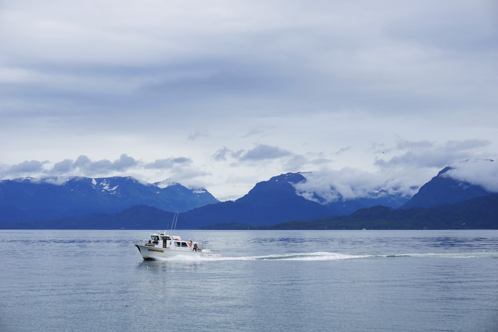 white boat on sea near mountain view