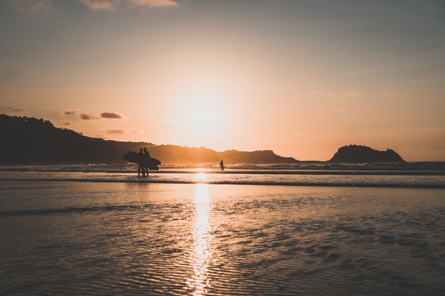 Due surfisti camminano nella Playa de Zarautz al tramonto