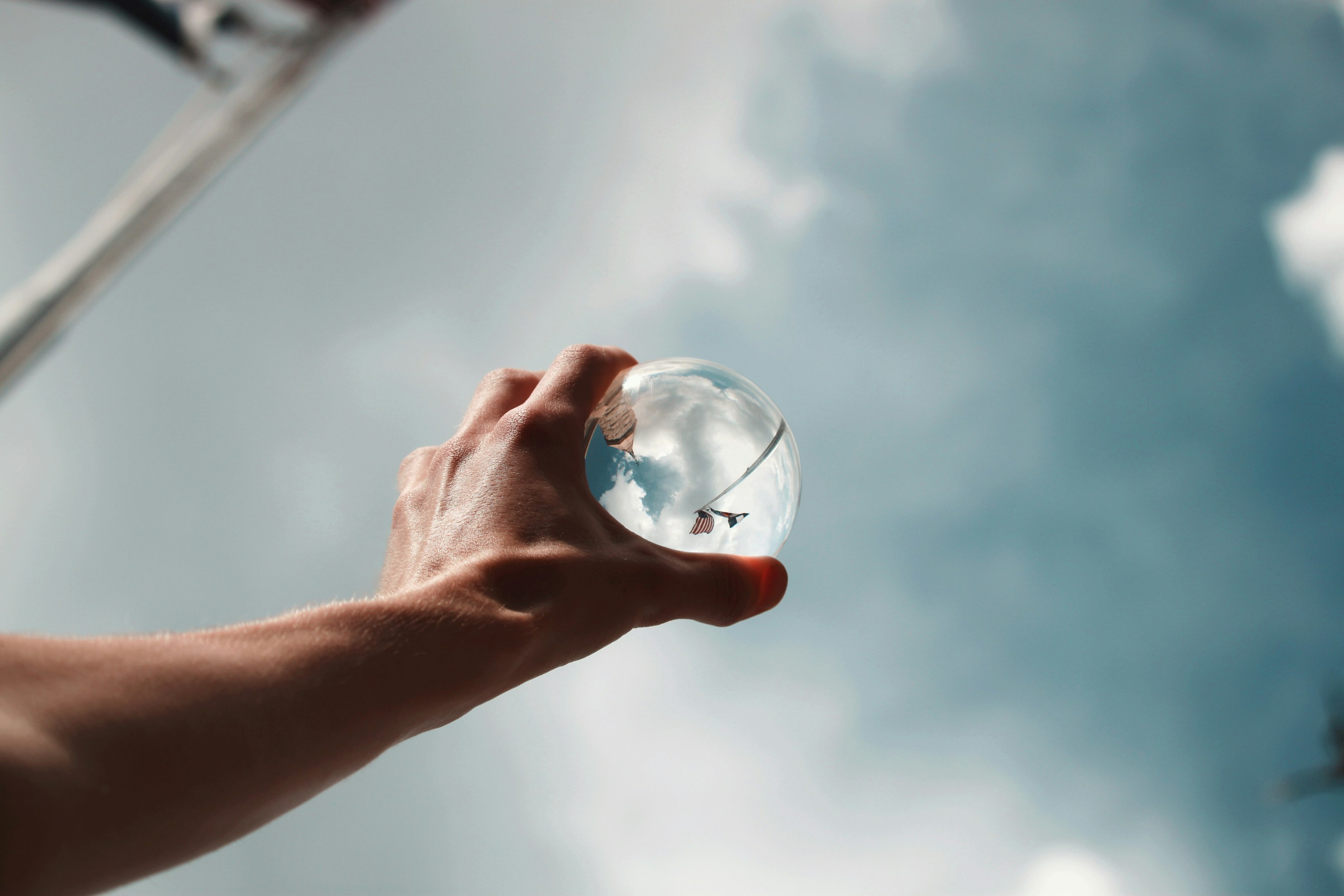 person holding glass ball towards the sky